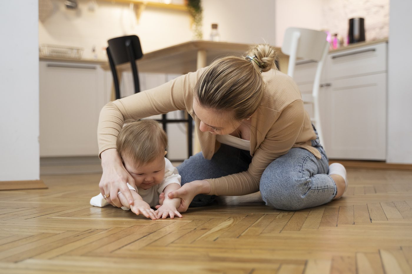 Mamă care își ajută bebelușul să stea în patru labe