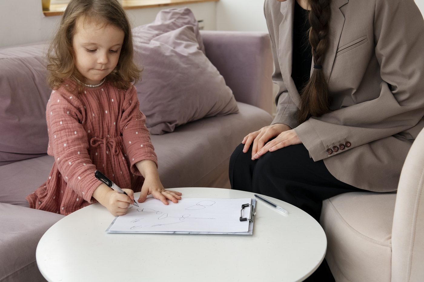 Specialist care observă o fetiță în timp ce desenează