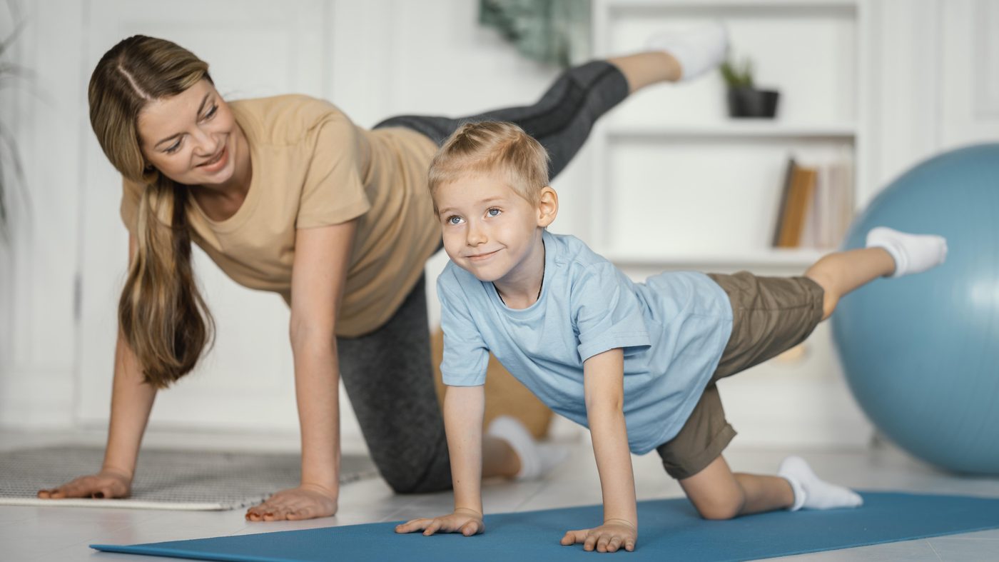 Kinetoterapeut și băiat în timpul unui exercițiu pe saltea