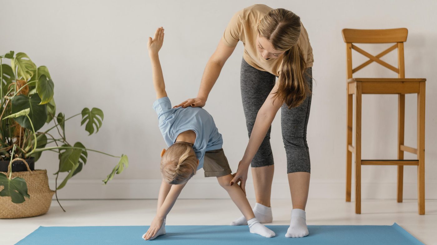 Specialist care sprijină o fetiță într-un exercițiu de echilibru